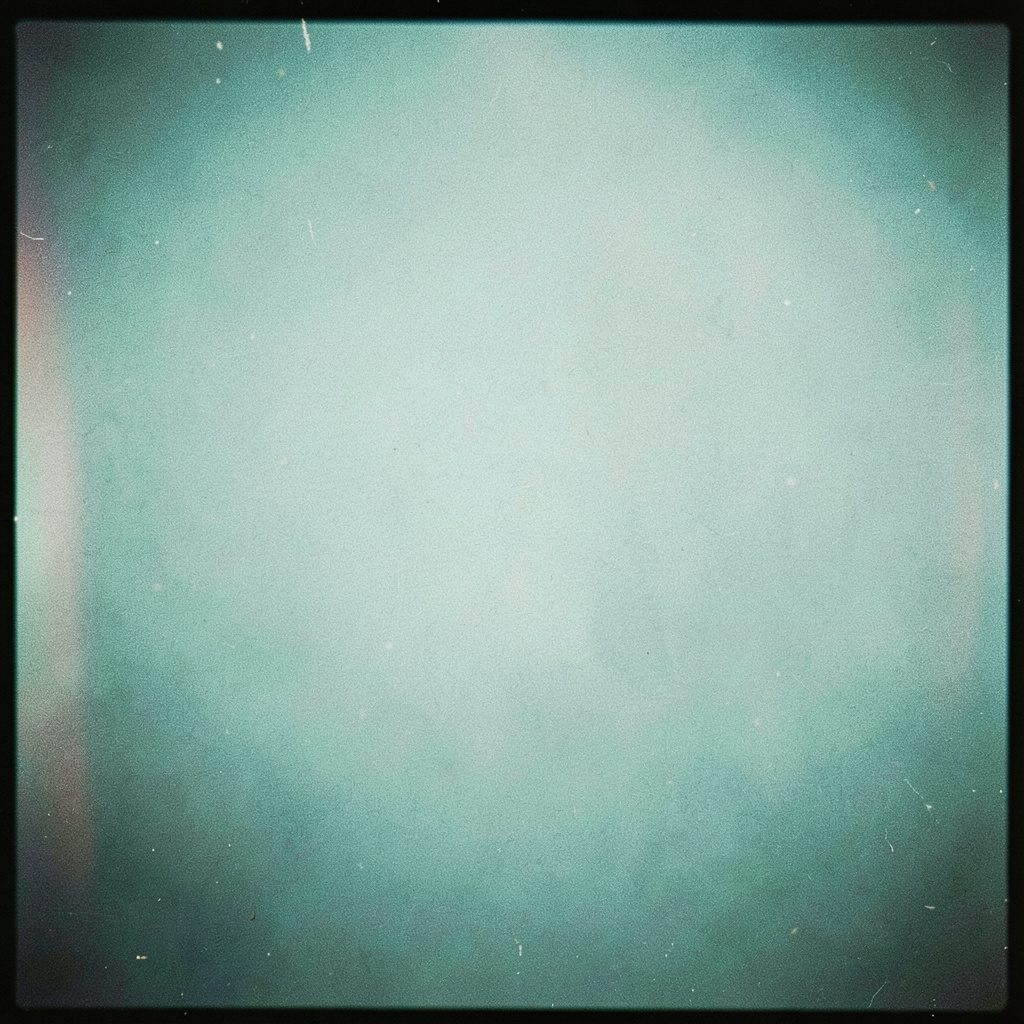 A moody flat-lay of a smartphone and tangled cables on a dark grainy surface, muted teal and charcoal tones, atmospheric film texture